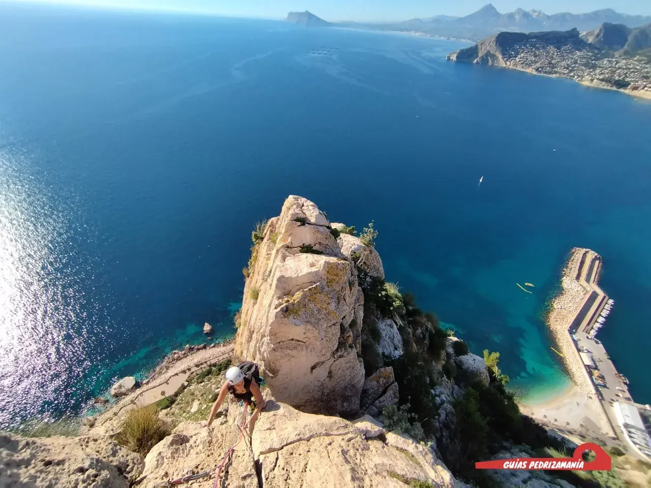 Escaladora en el Peñón de Calpe, con el mar azul y la costa al fondo.