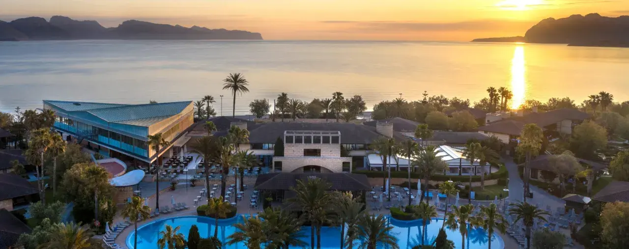 Resortanlage mit Pool und Meerblick bei Sonnenuntergang.