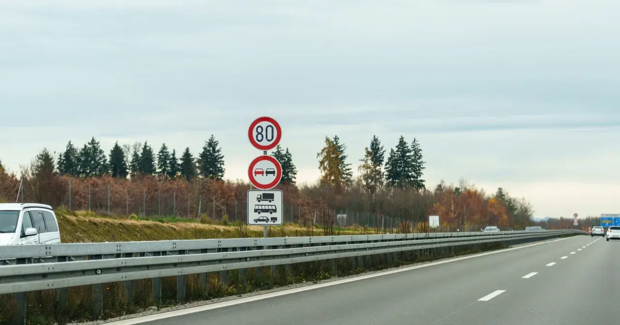 Niemieckie znaki drogowe: ograniczenie prędkości do 80 km/h, zakaz wyprzedzania dla ciężarówek i samochodów osobowych.