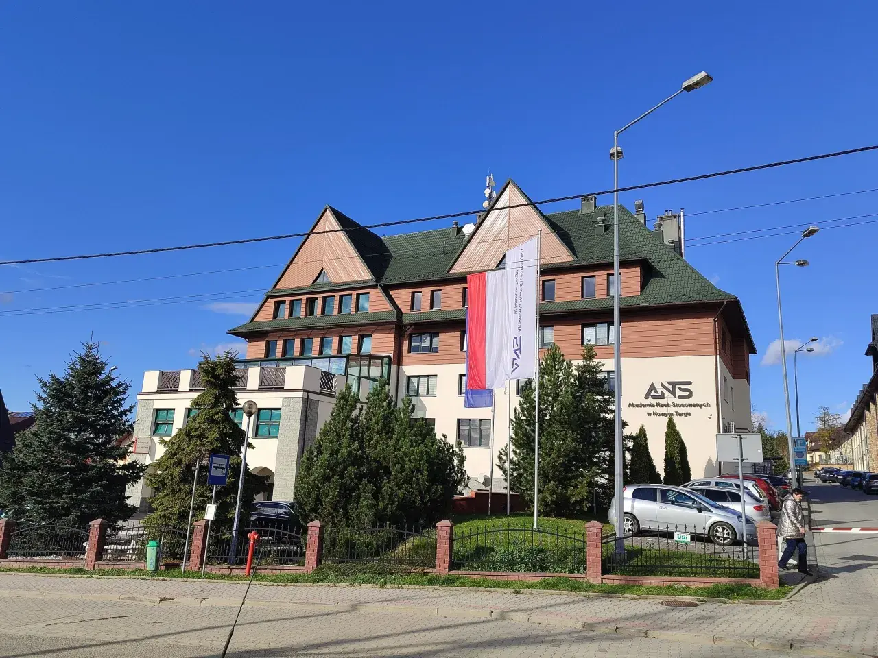 Budynek Akademii Nauk Stosowanych w Nowym Targu z polską flagą.