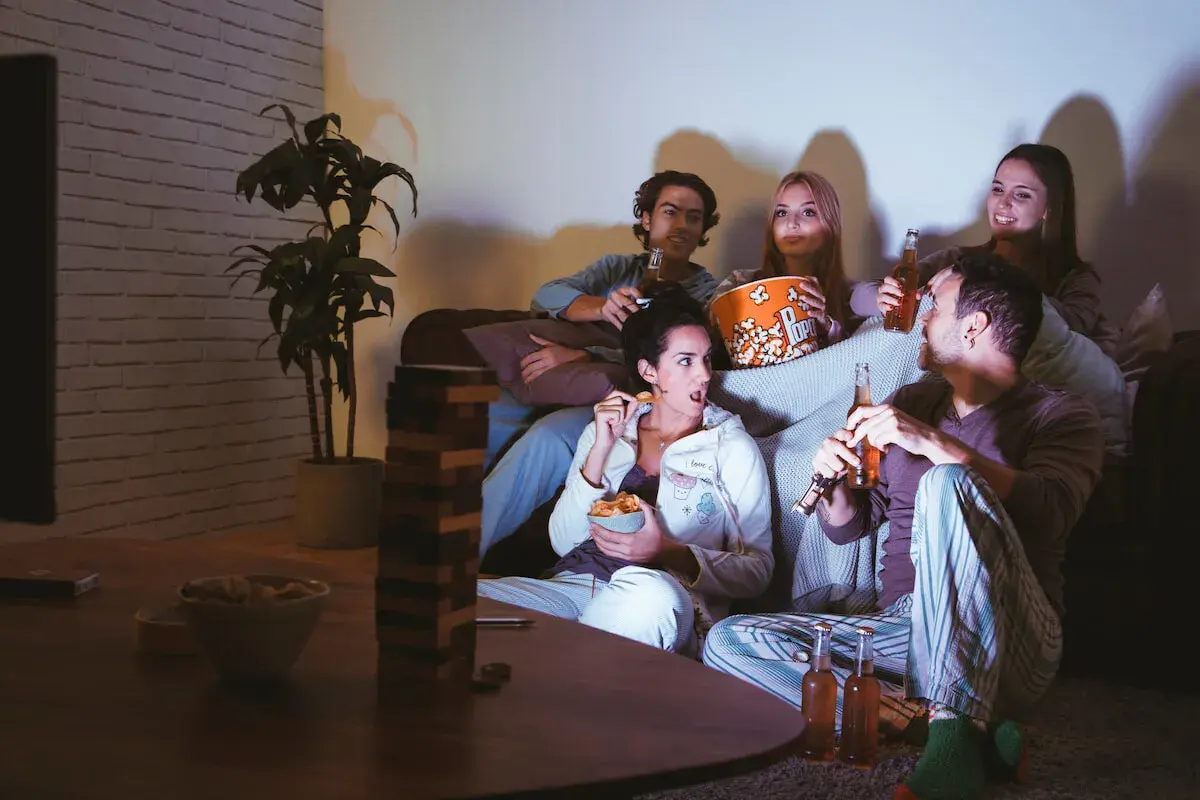 Ragazzi sul divano, popcorn e birra per una serata film.