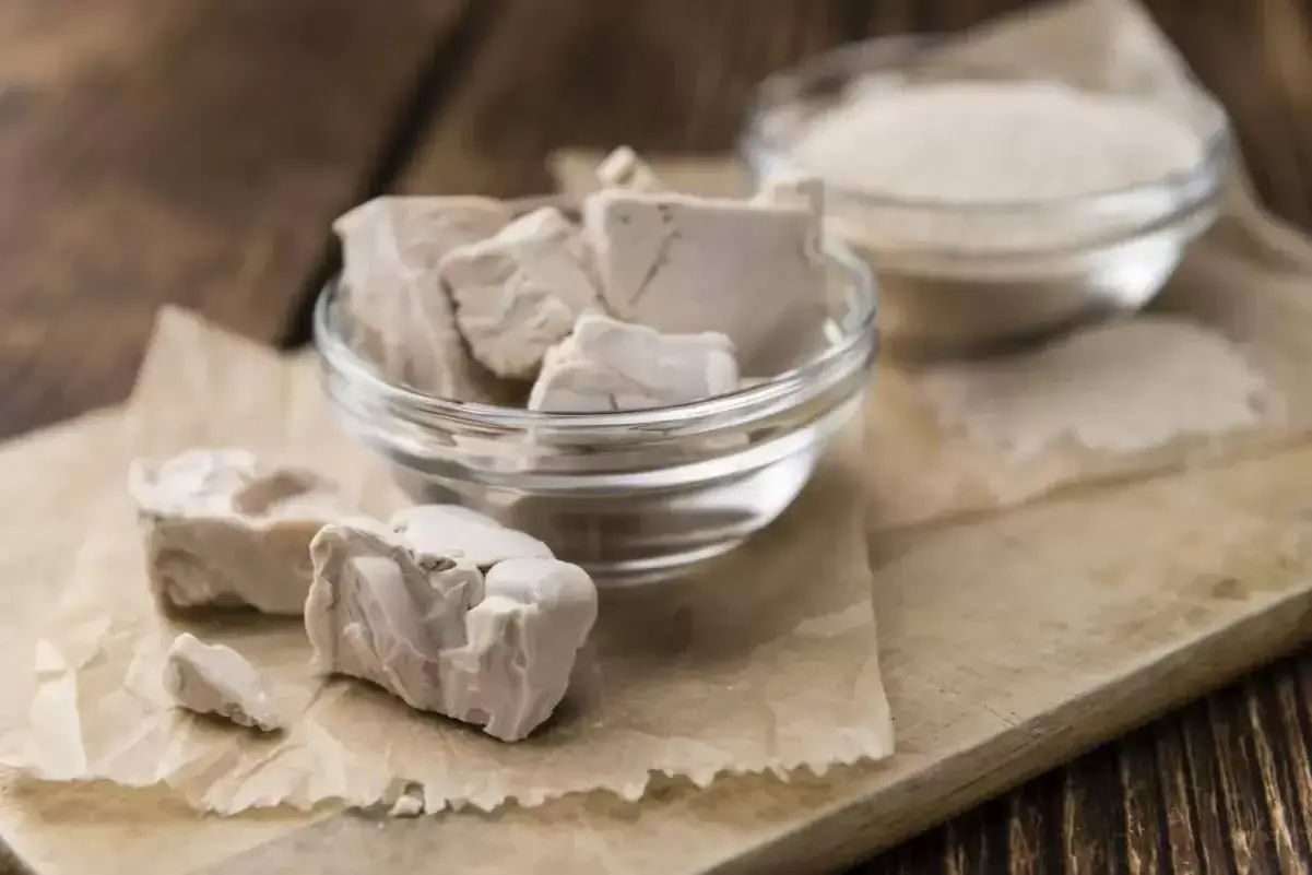 Blocs de levure fraîche périmée dans un bol en verre, prêts à être jetés. À côté, une autre coupelle contient de la levure sèche.