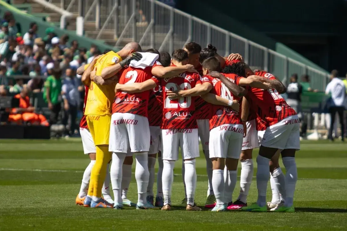 Piłkarze RCD Mallorca w czerwonych strojach tworzą zwarty krąg przed meczem z Valencią CF.