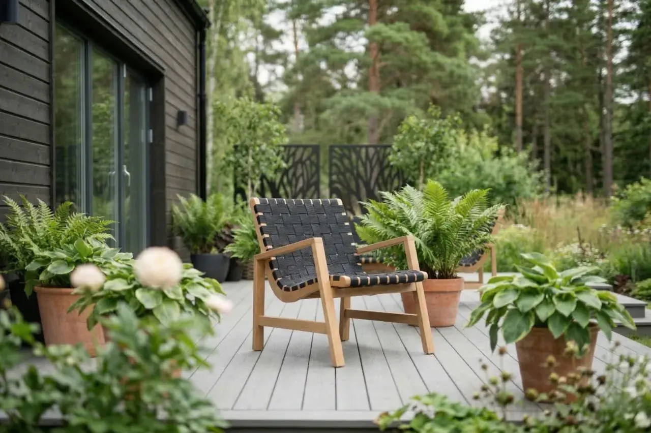 En modern fåtölj med trästomme och flätad sits i plast står på en altan omgiven av grönska.