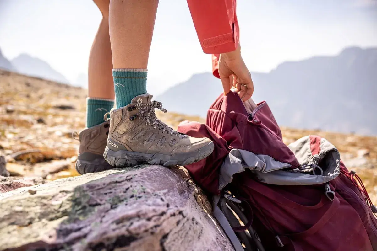 A hiker prepares for adventure, checking their boots. Are boots sized differently than shoes? These sturdy Oboz boots are ready for the trail.