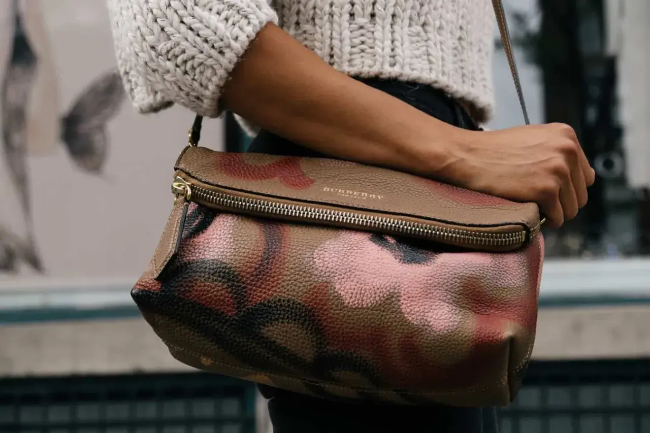 Torba Burberry z motywem moro, przykład brytyjskich marek odzieżowych, noszona przez kobietę w swetrze.