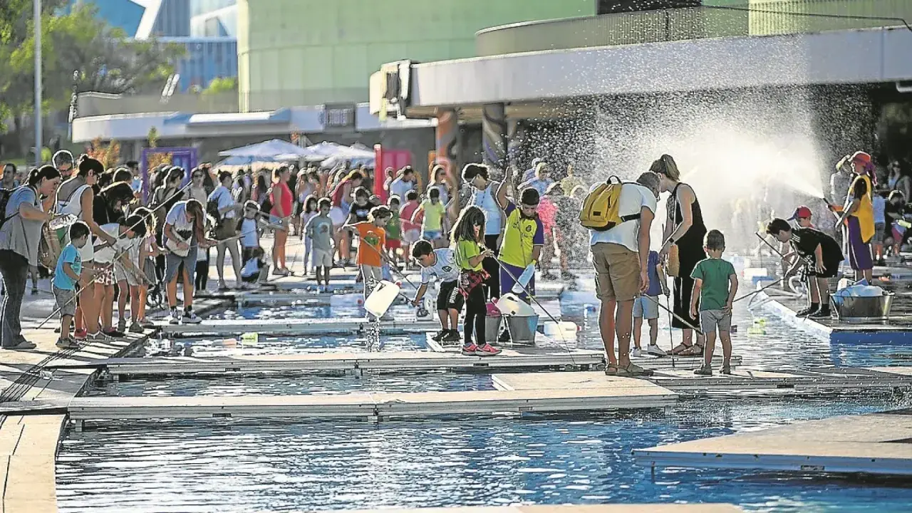 Niños y adultos disfrutan de un **espacio río y juego** con actividades acuáticas bajo el sol.