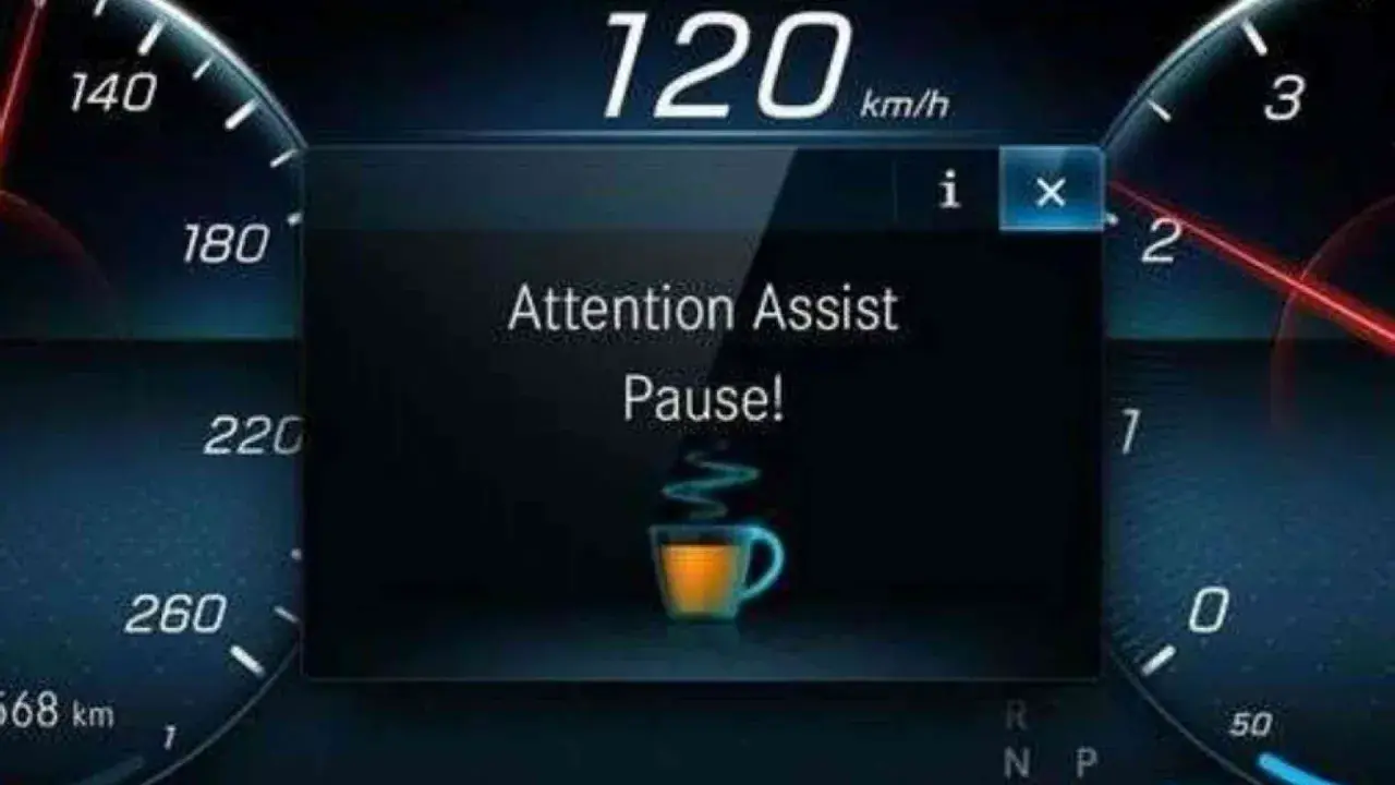 Il display mostra "Attention Assist Pause!" con una tazzina di caffè, indicando come funziona il rilevatore di stanchezza Volkswagen: suggerisce una pausa.