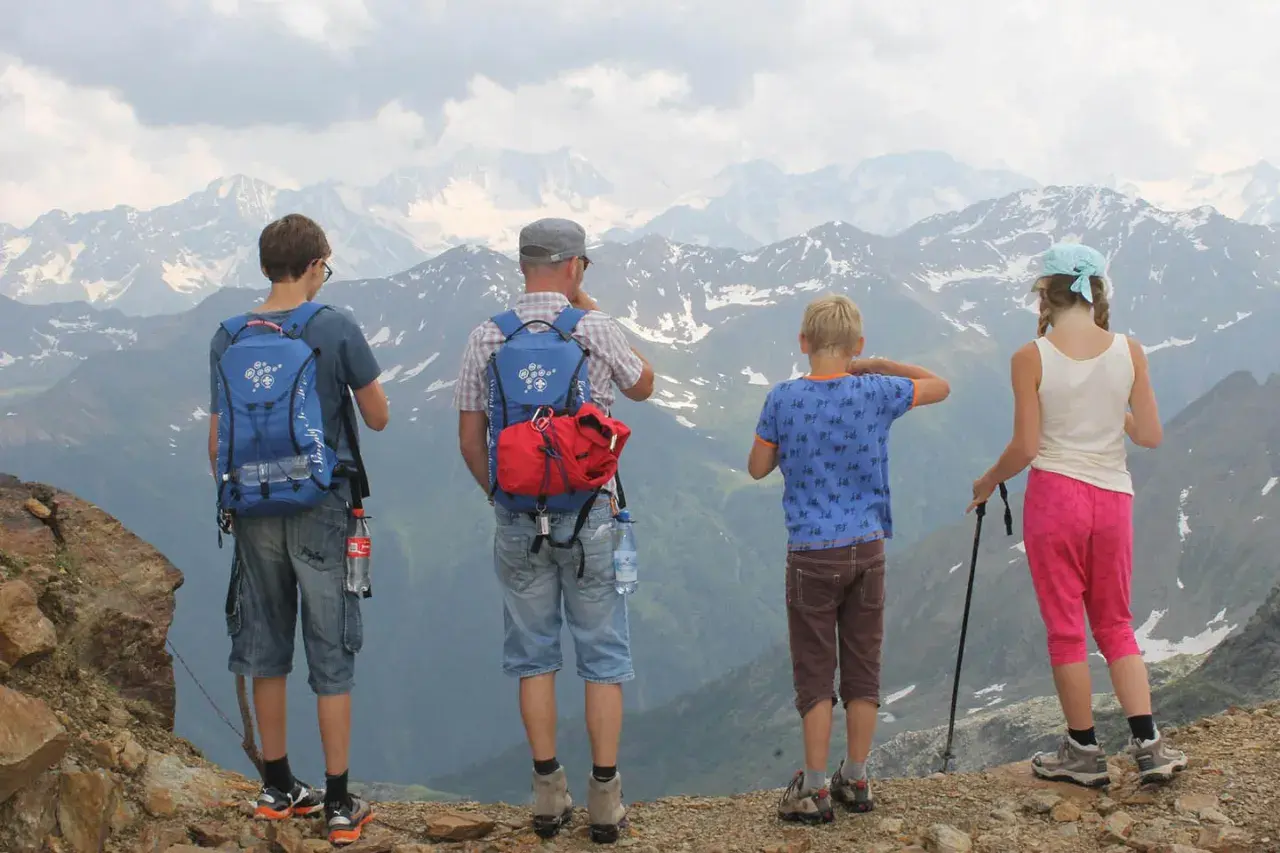 Familie genießt die Aussicht bei einer Bergtour mit Kindern. Die beeindruckende Berglandschaft erstreckt sich bis zum Horizont.