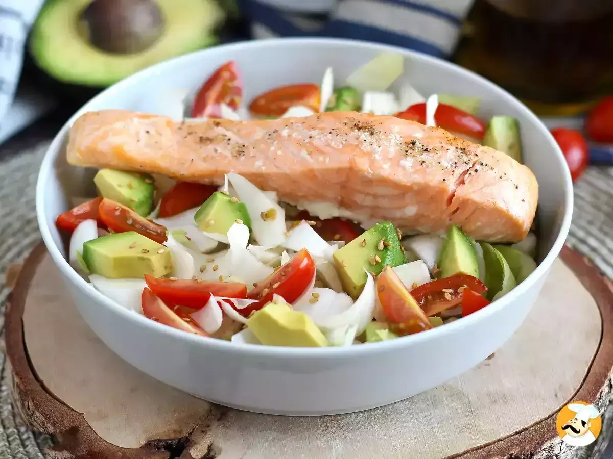 Delizioso filetto di salmone cotto su un letto di avocado, pomodorini e cipolla bianca. Un piatto leggero e gustoso, perfetto come secondi di pesce.