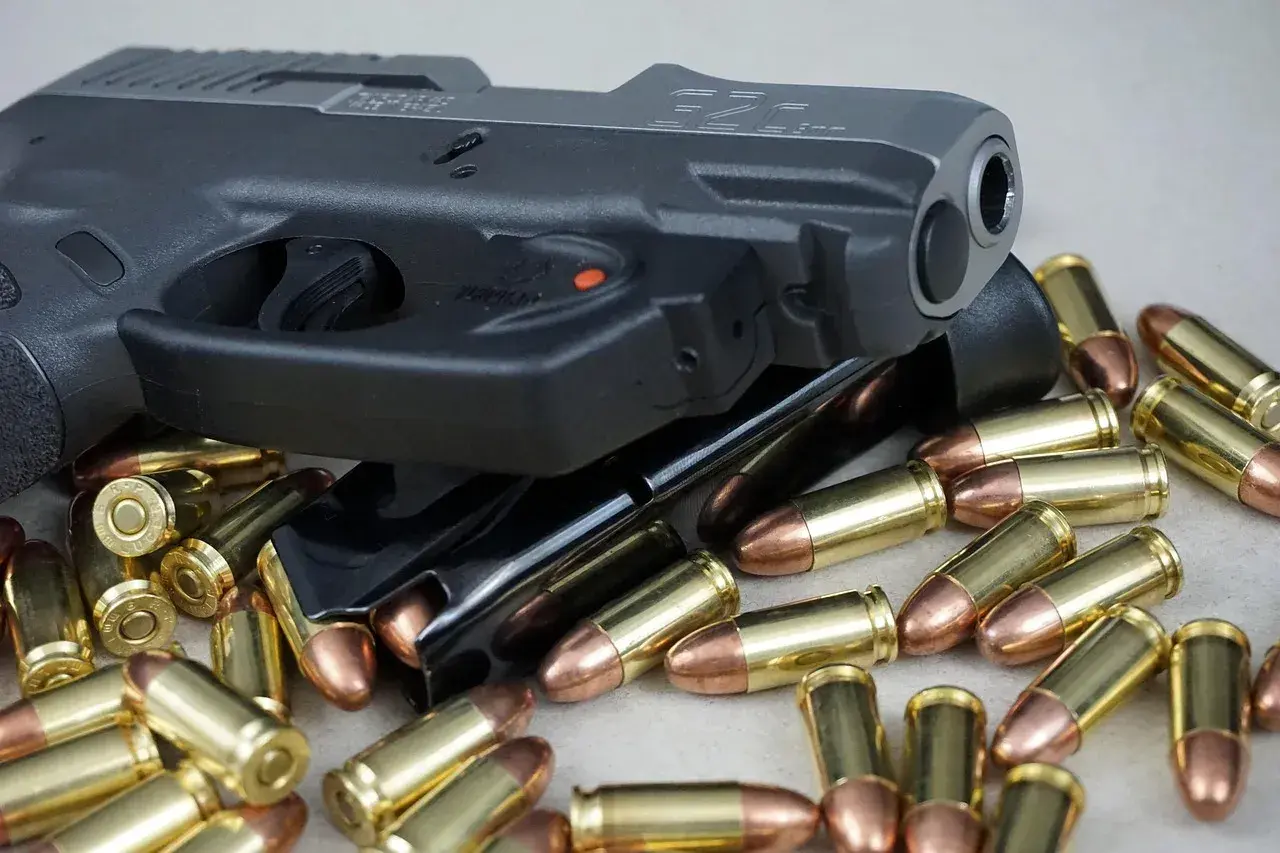 Pistolet i magazynki otoczone nabojami. Różne rodzaje pistoletów mogą być prezentowane w podobnych ujęciach.