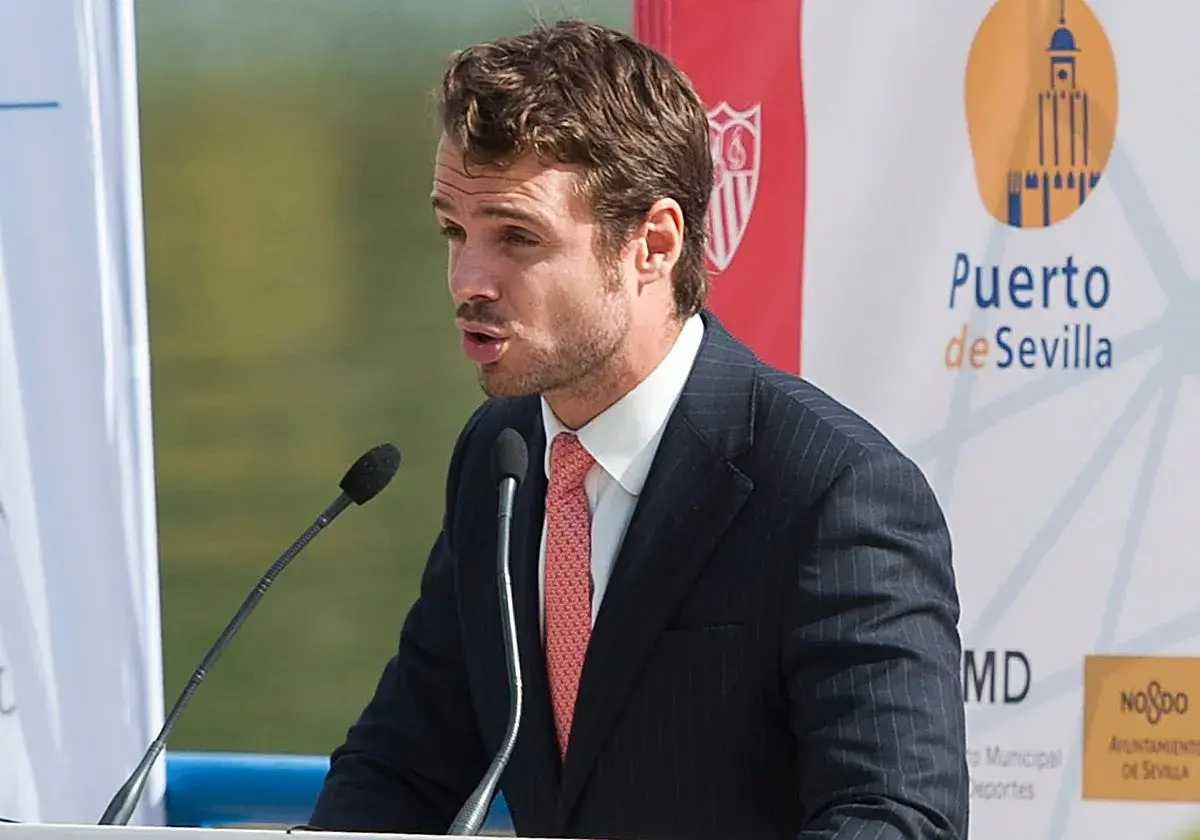José María González de Caldas, con traje y corbata, habla en un atril con micrófonos. Fondo con logo de Puerto de Sevilla.