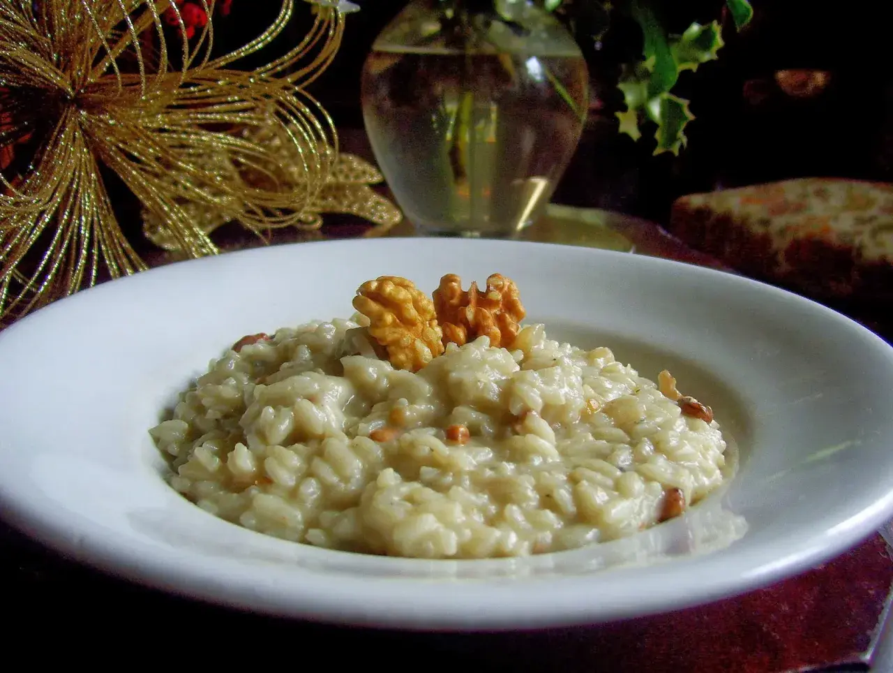 Kremowe risotto z gorgonzolą i orzechami włoskimi, ozdobione złotą dekoracją.