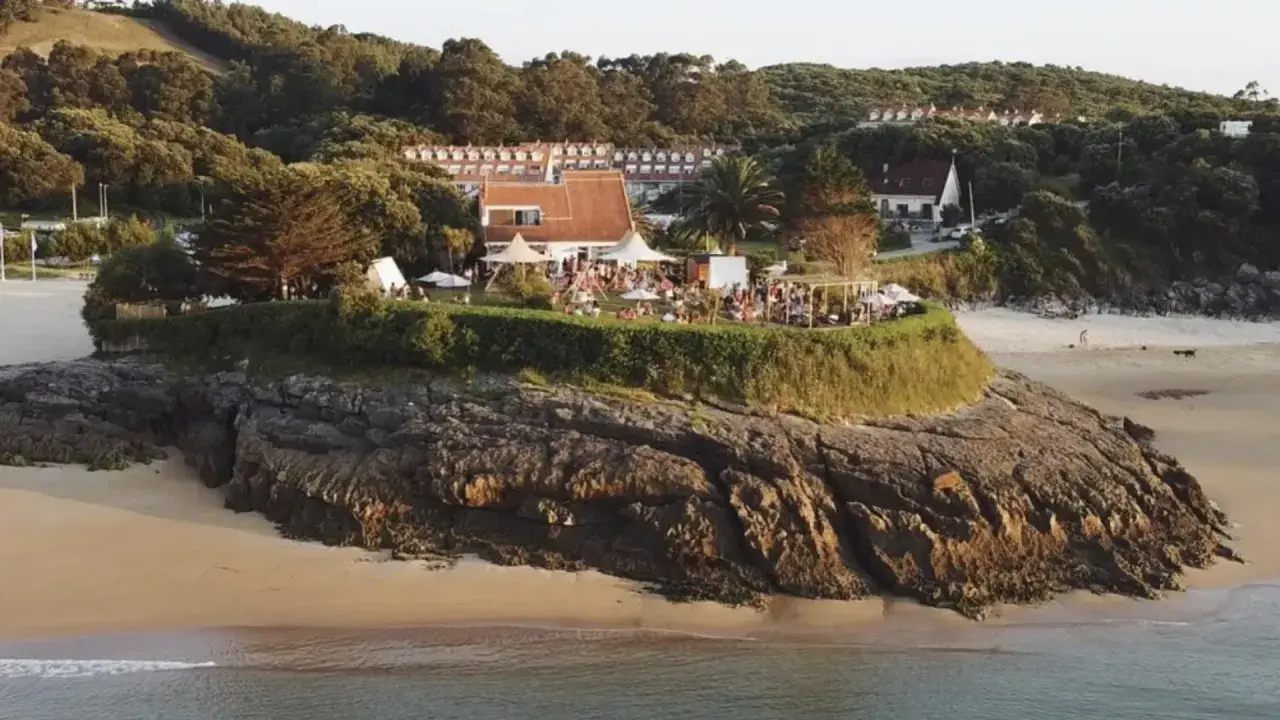 Evento en la playa madre Cantabria, con gente disfrutando de la terraza y el ambiente festivo, quizás antes de unos conciertos.