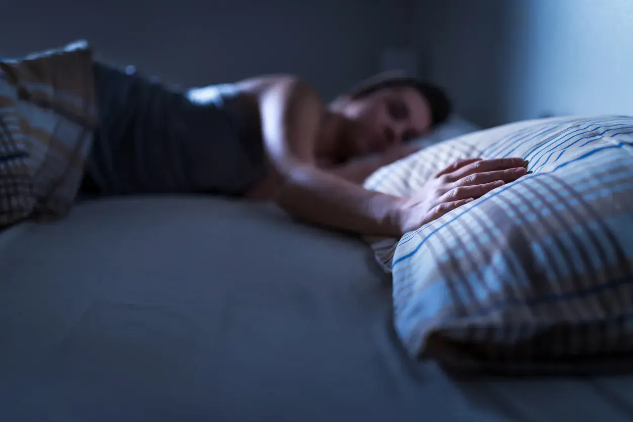 Persona durmiendo, mano sobre almohada. ¿Qué significa soñar con tu padre fallecido?