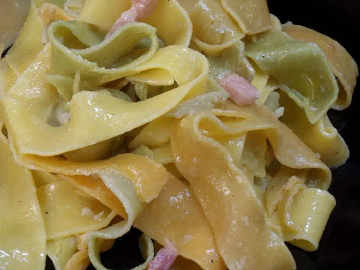 Pâtes larges, jaunes et vertes, nappées d'une sauce crémeuse et parsemées de lardons. Un délice de sauce carbonara.