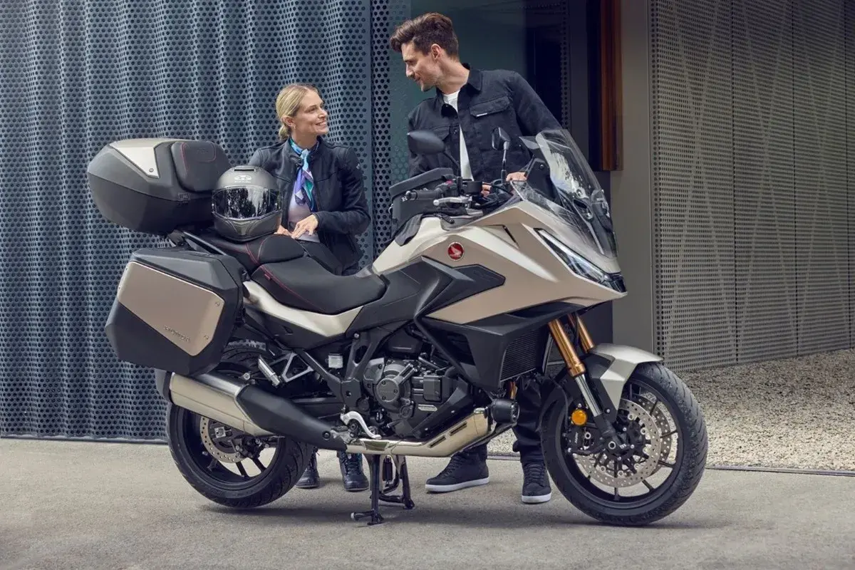 Para zwiedzająca motocykle z automatyczną skrzynią biegów. Nowoczesny turystyczny motocykl Honda z kuframi.