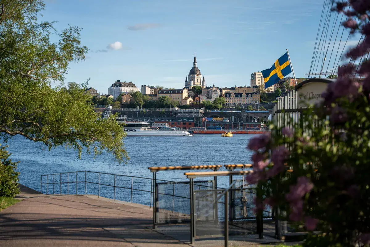 Ein perfekter Blick auf Stockholm für Ihr 4 Tage Stockholm Programm: Die Skyline mit Kirche, die schwedische Flagge und ein Boot auf dem Wasser.