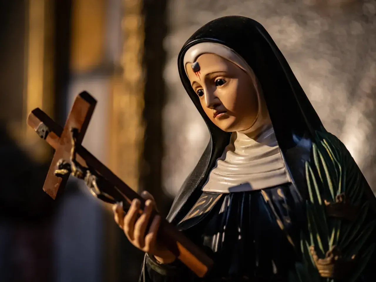 Figurka świętej Rity od spraw beznadziejnych trzyma krzyż.