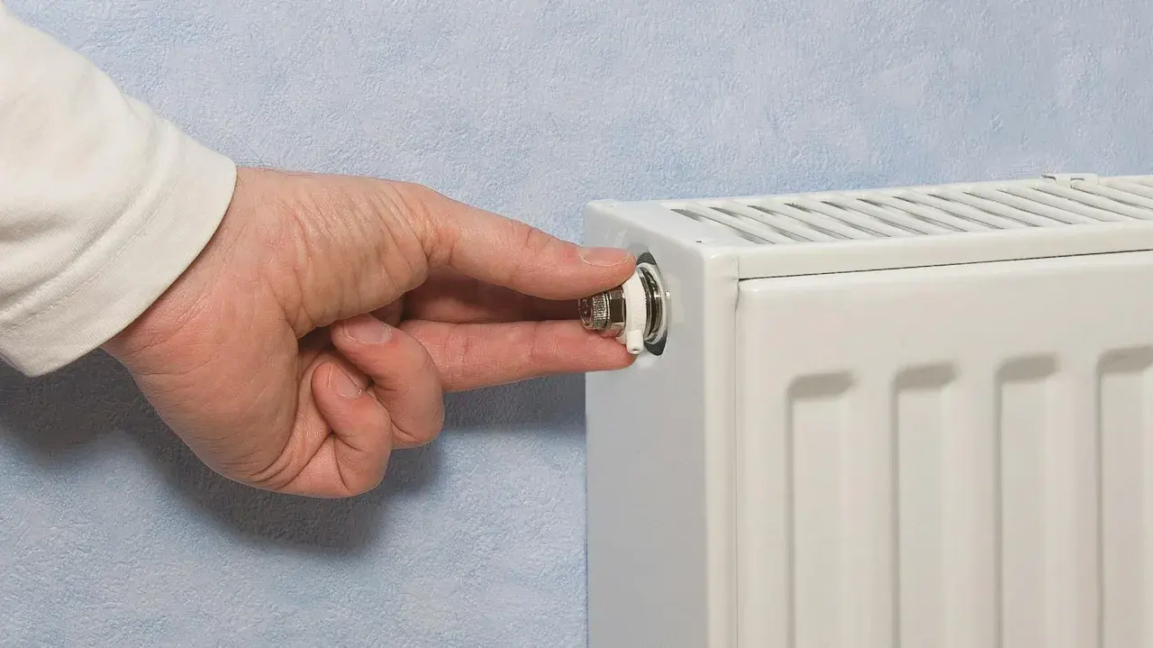 Mano che gira la valvola di uno spurgo termosifone. È il momento di capire quando spurgare i termosifoni per un riscaldamento efficiente.