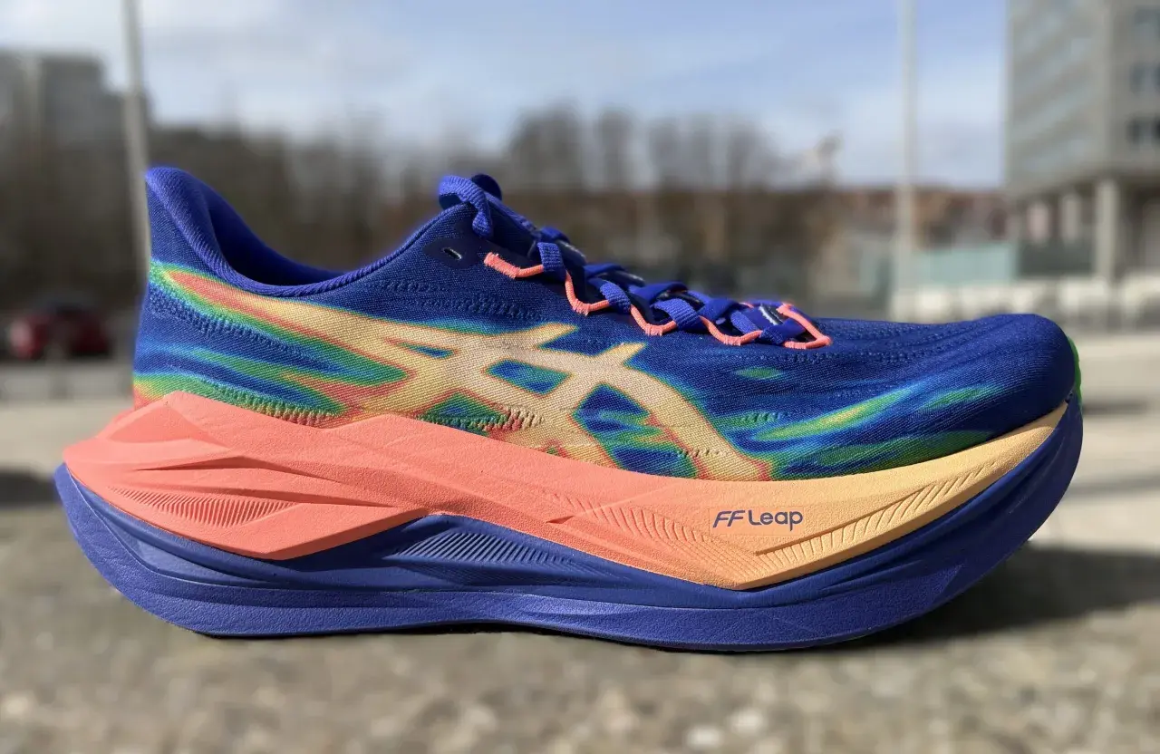 Blauer Laufschuh mit Regenbogenmuster und orangefarbener Sohle, bereit für einen superblast 3.