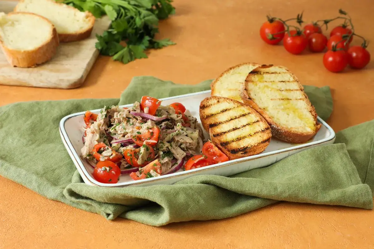 Deliziosa insalata di bollito con pomodorini, cipolla rossa e pane abbrustolito, un piatto fresco e saporito.