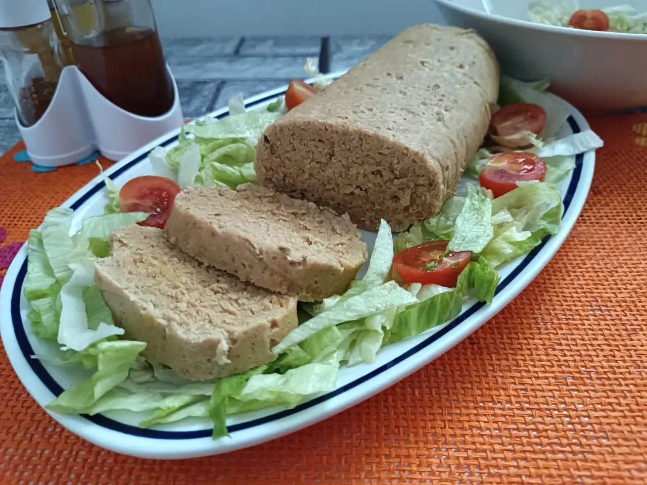 Un gustoso polpettone di tonno, affettato e servito su un letto di lattuga fresca con pomodorini.