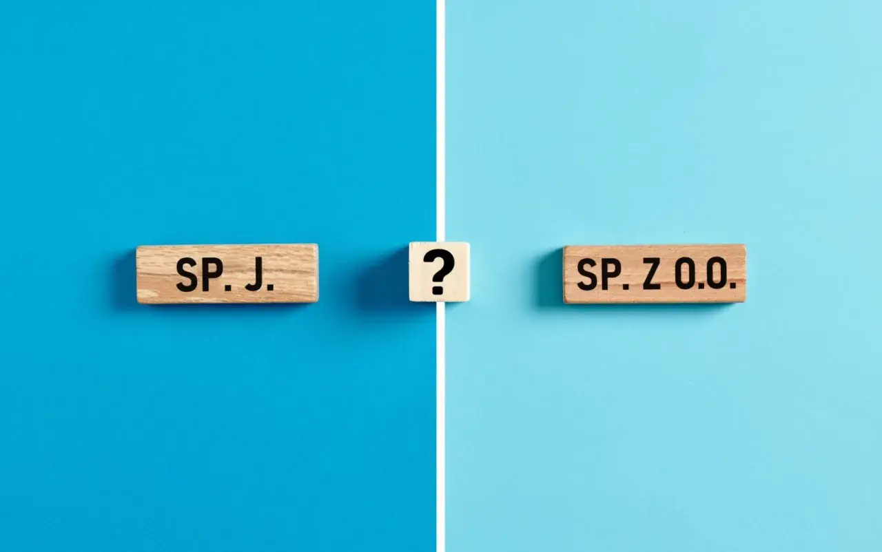 Drewniane klocki z napisami "SP. J." i "SP. Z O.O." oraz znak zapytania na niebieskim tle.