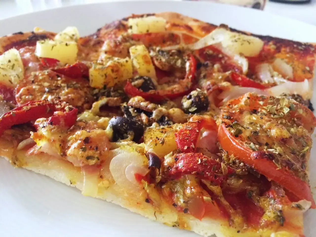 En bit pizza med ananas, oliver och paprika. Ett perfekt glutenfri pizzadeg recept för en god middag.