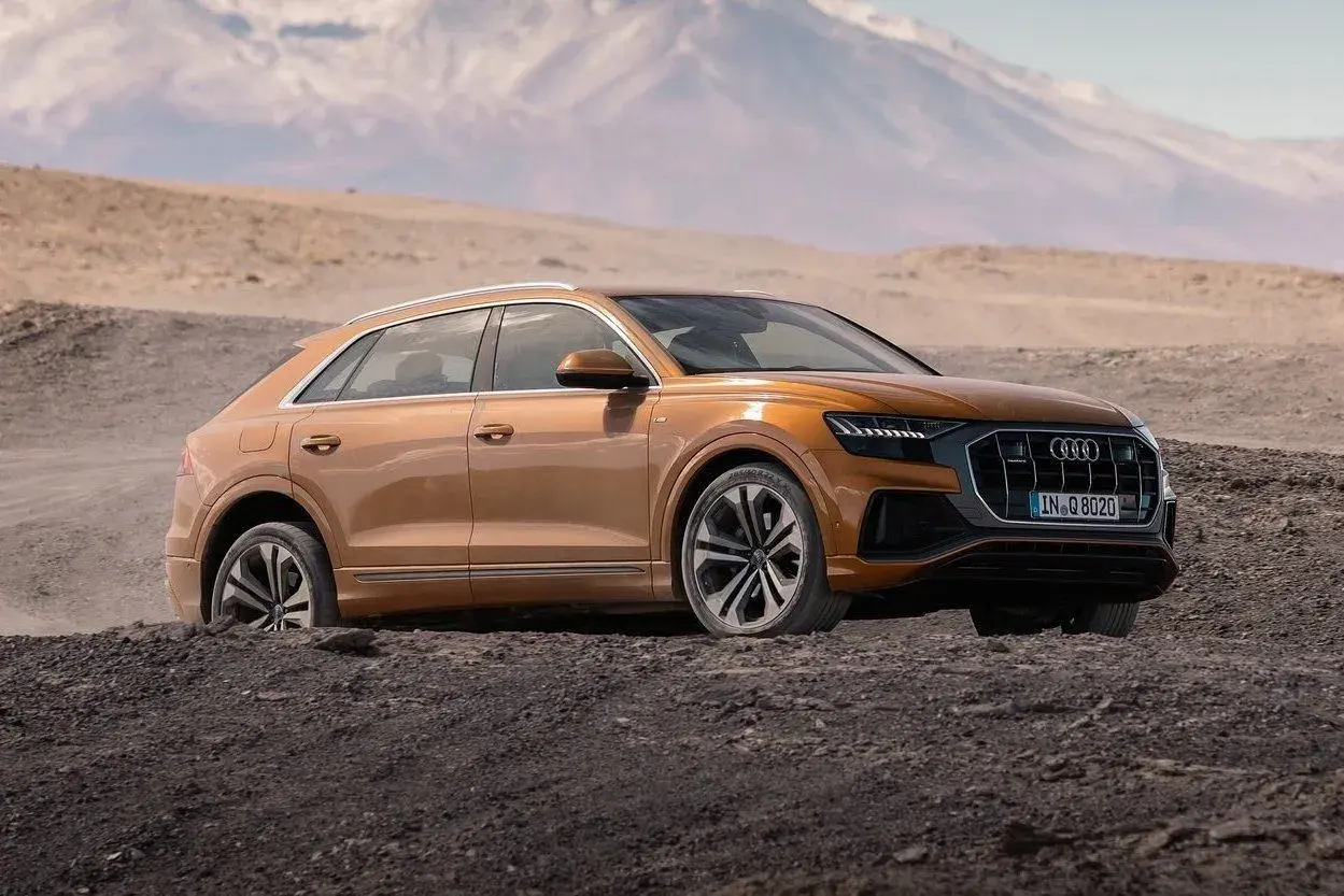 Pomarańczowy Audi Q8 w terenie, gotowy na przygodę. Sprawdź aktualną audi q8 cena i odkryj jego możliwości.