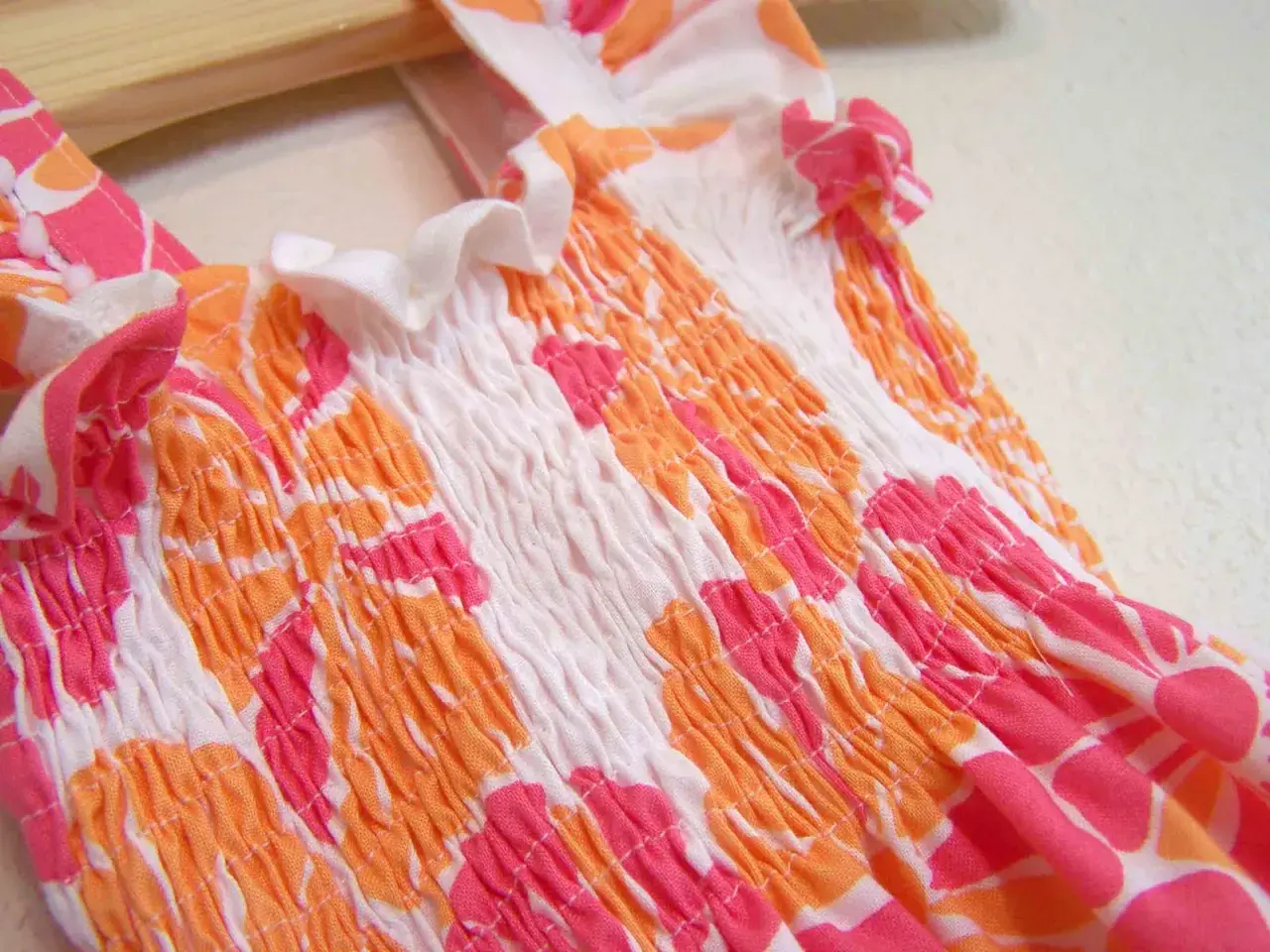 Close-up of a smocked garment with a floral pattern, showing how to sew with elastic thread for a gathered effect.