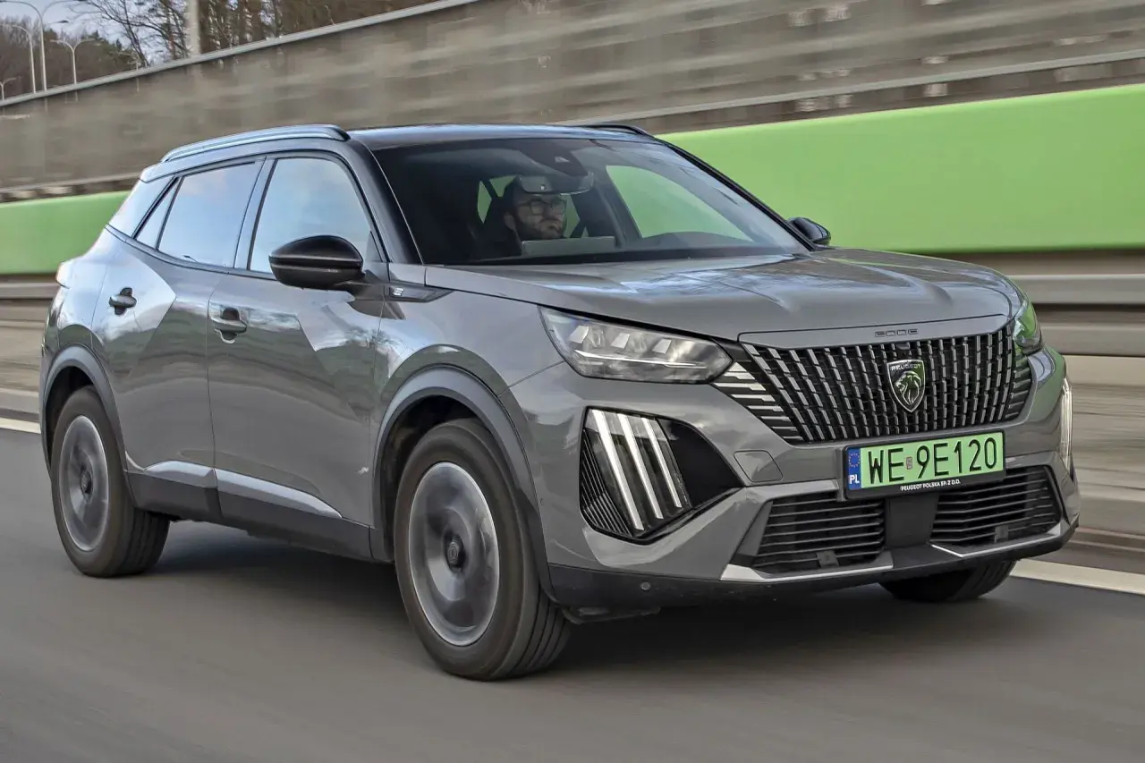 Szary Peugeot 2008 na drodze, kierowca w okularach. Sprawdź aktualną peugeot 2008 cena.