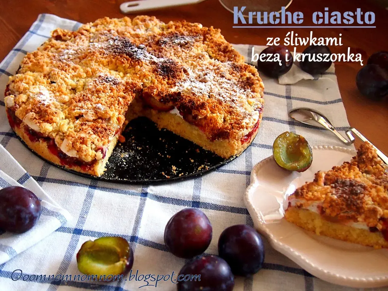 Pyszne kruche ciasto ze śliwkami i kruszonką, posypane cukrem pudrem. Obok leżą świeże śliwki.