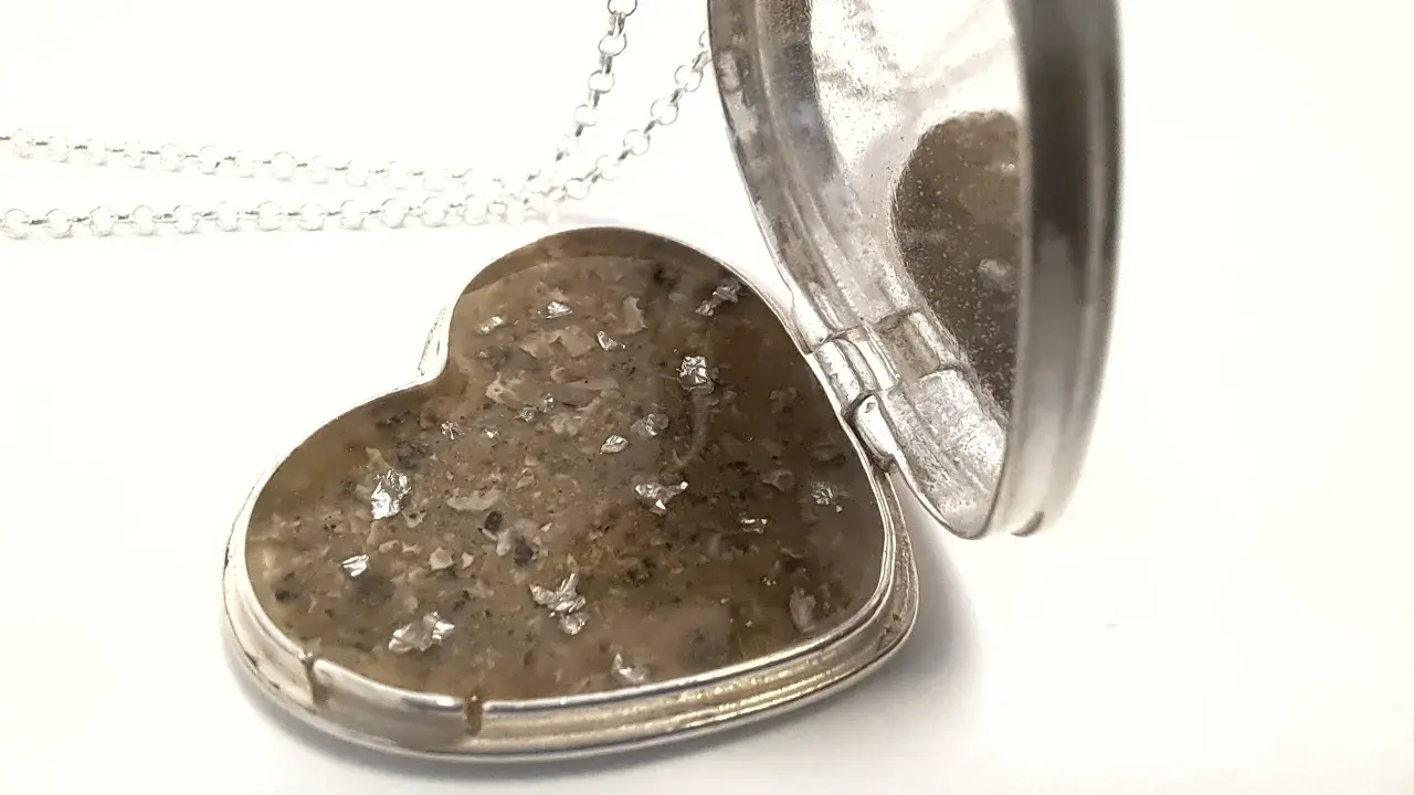 Srebrne serce-medalion z zawartością prochów, przypominające diament z prochów.