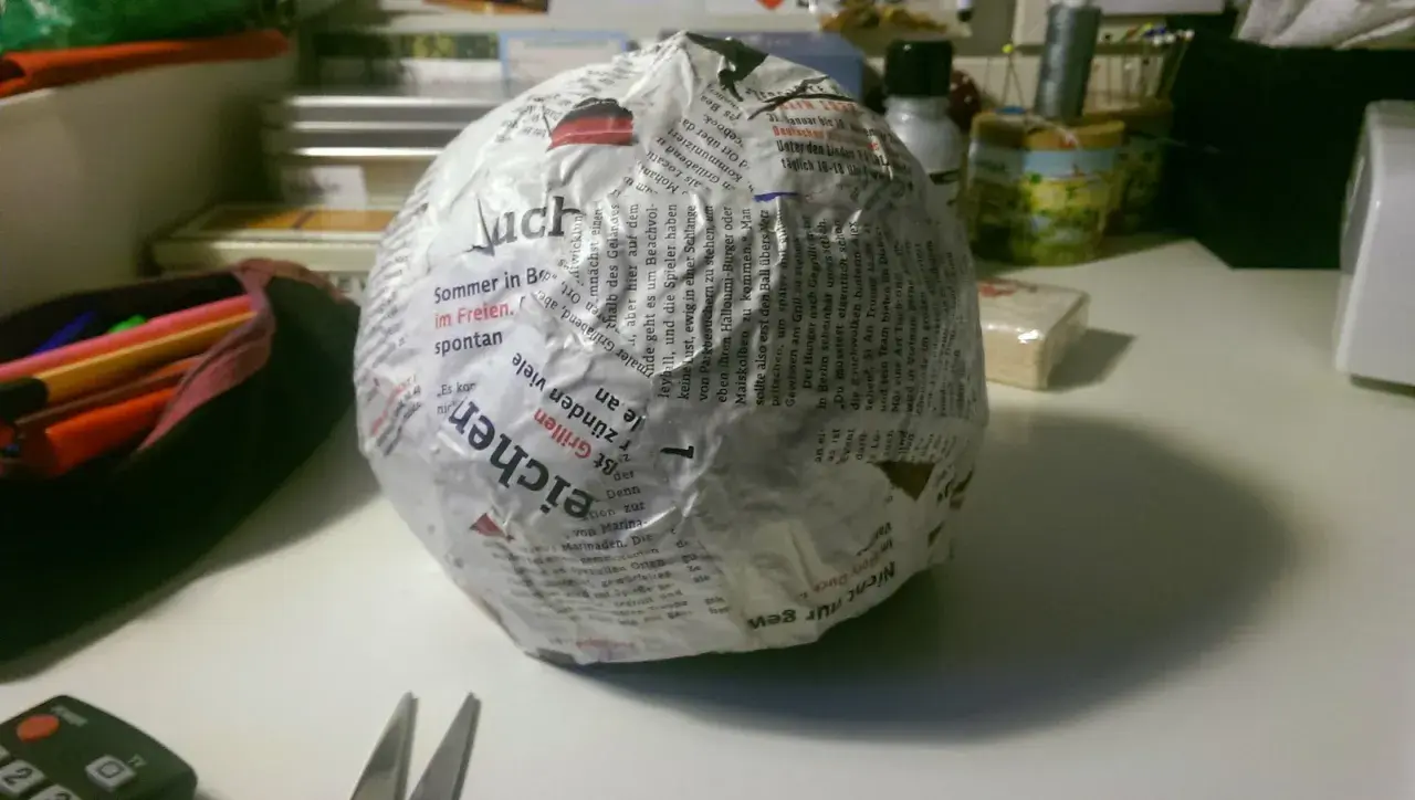 Papierkugel mit Zeitungspapier und Kleister. Die Frage, wie lange braucht Mehlkleister zum trocknen, beschäftigt den Bastler.