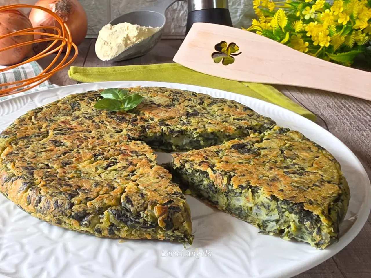 Frittata di spinaci dorata e soffice, guarnita con basilico fresco, pronta per essere gustata. Ingredienti freschi sullo sfondo.