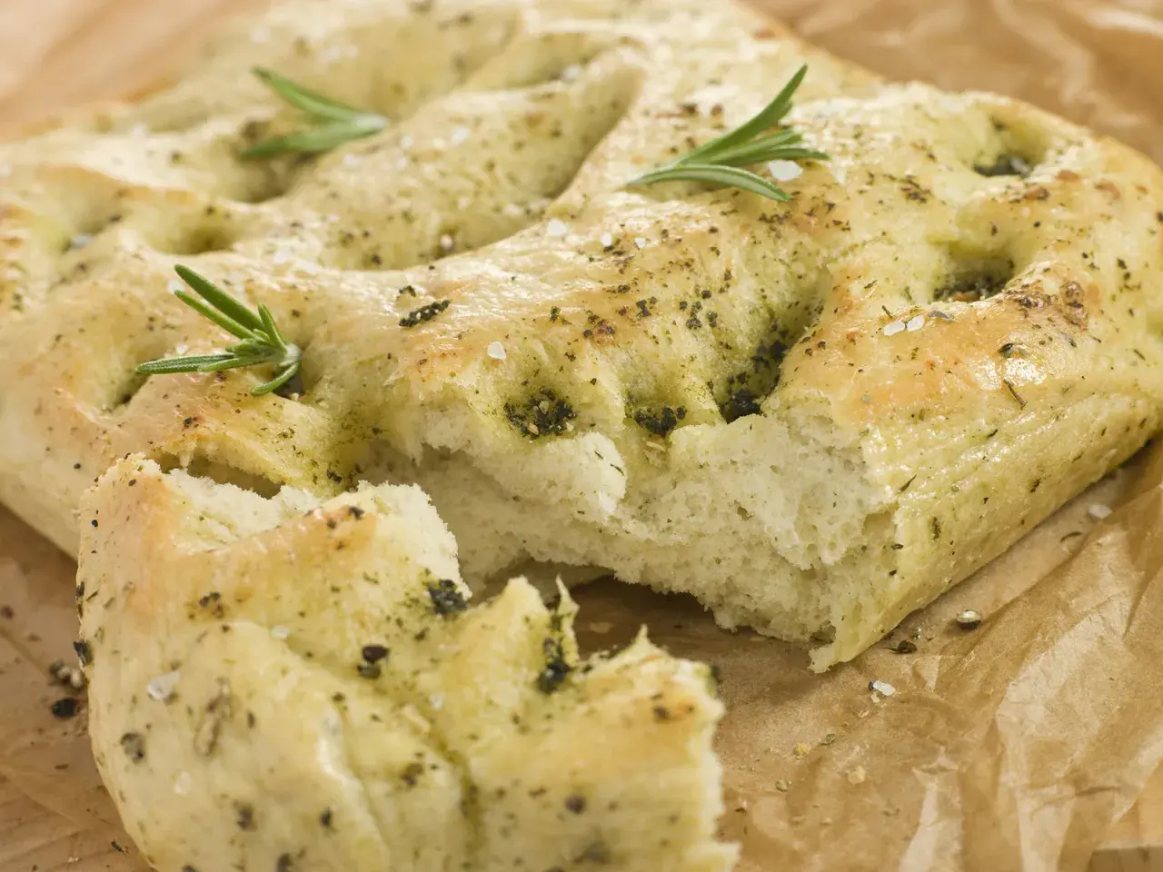 Frisch gebackene italienische Focaccia mit Rosmarin und grobem Salz, auf Backpapier.