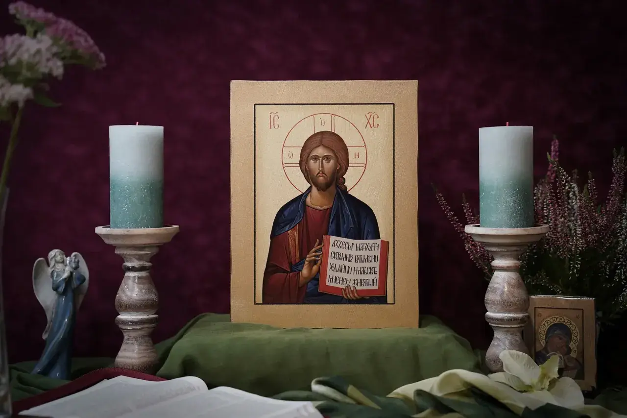 Ikona Chrystusa Pantokratora, otoczona świecami i kwiatami, emanuje spokojem.