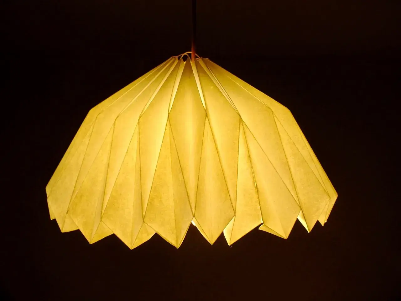 Oświetlony, żółty abażur z papieru, złożony jak origami. Inspiracja, jak zrobić abażur z papieru, dla Twojego wnętrza.