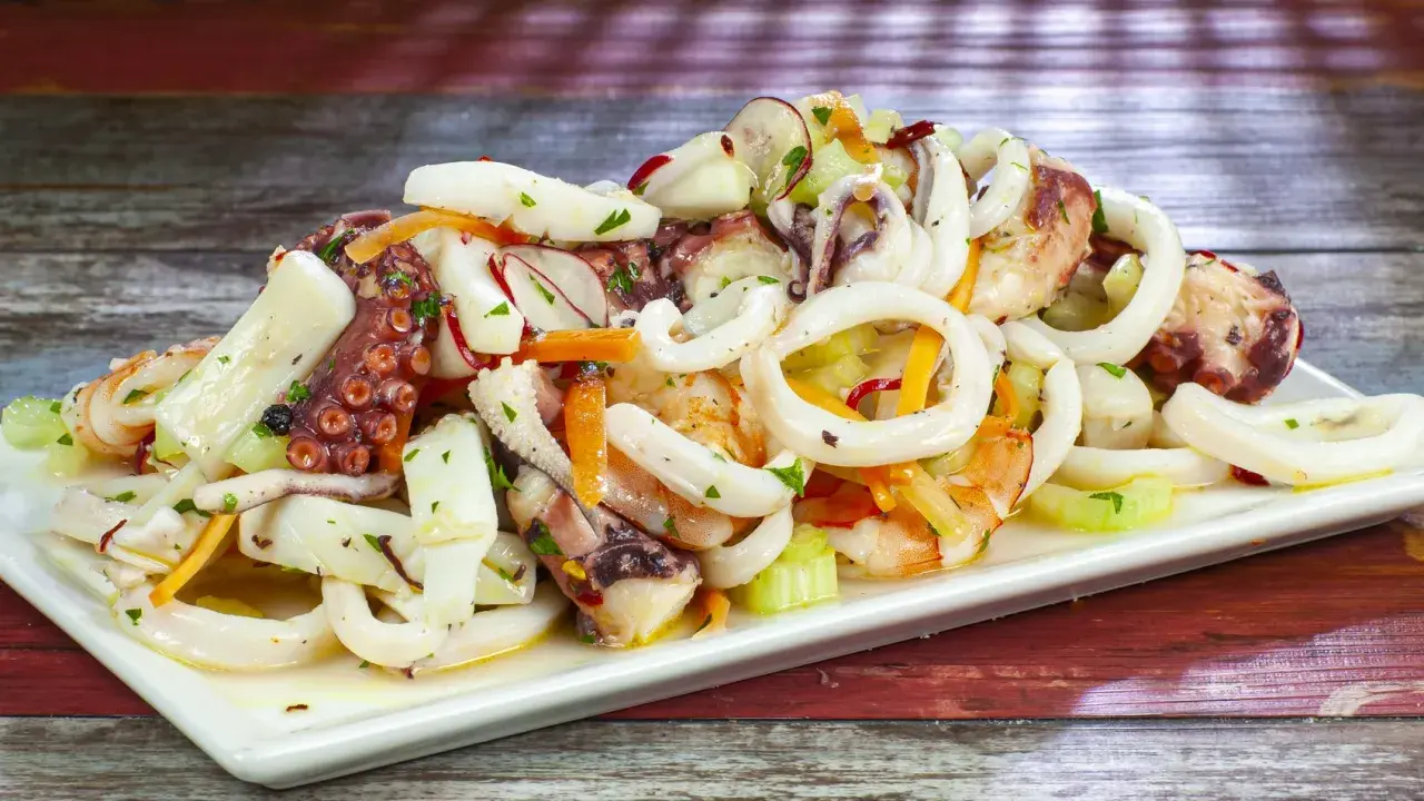 Deliziosa insalata di mare con anelli di calamaro, tentacoli di polpo e gamberi, condita con verdure fresche.