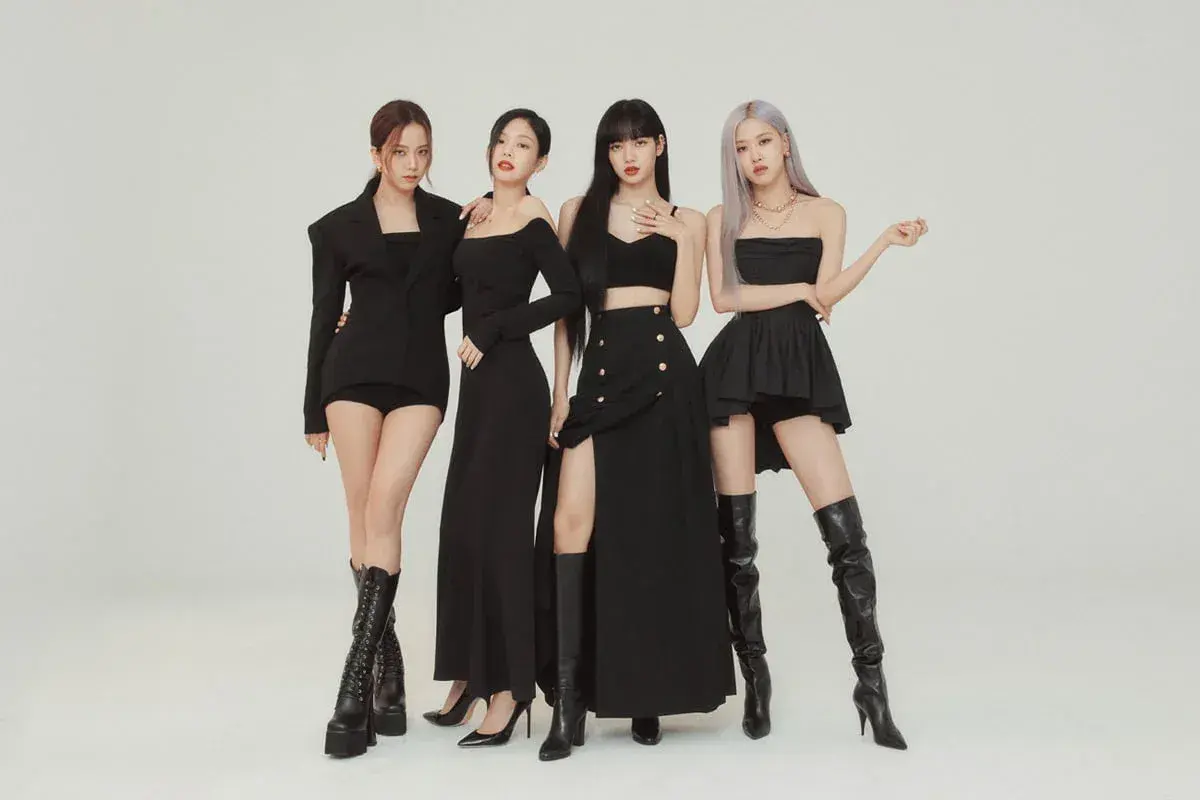 Cztery członkowie BLACKPINK w czarnych, stylowych strojach pozują do zdjęcia.