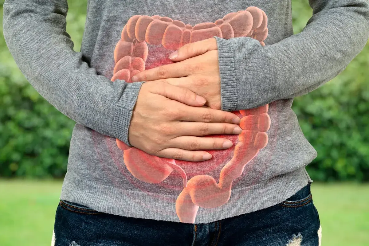 Personne tenant son ventre, avec une image superposée d'intestins rouges. Selles liquides comme de l'eau que faire ?