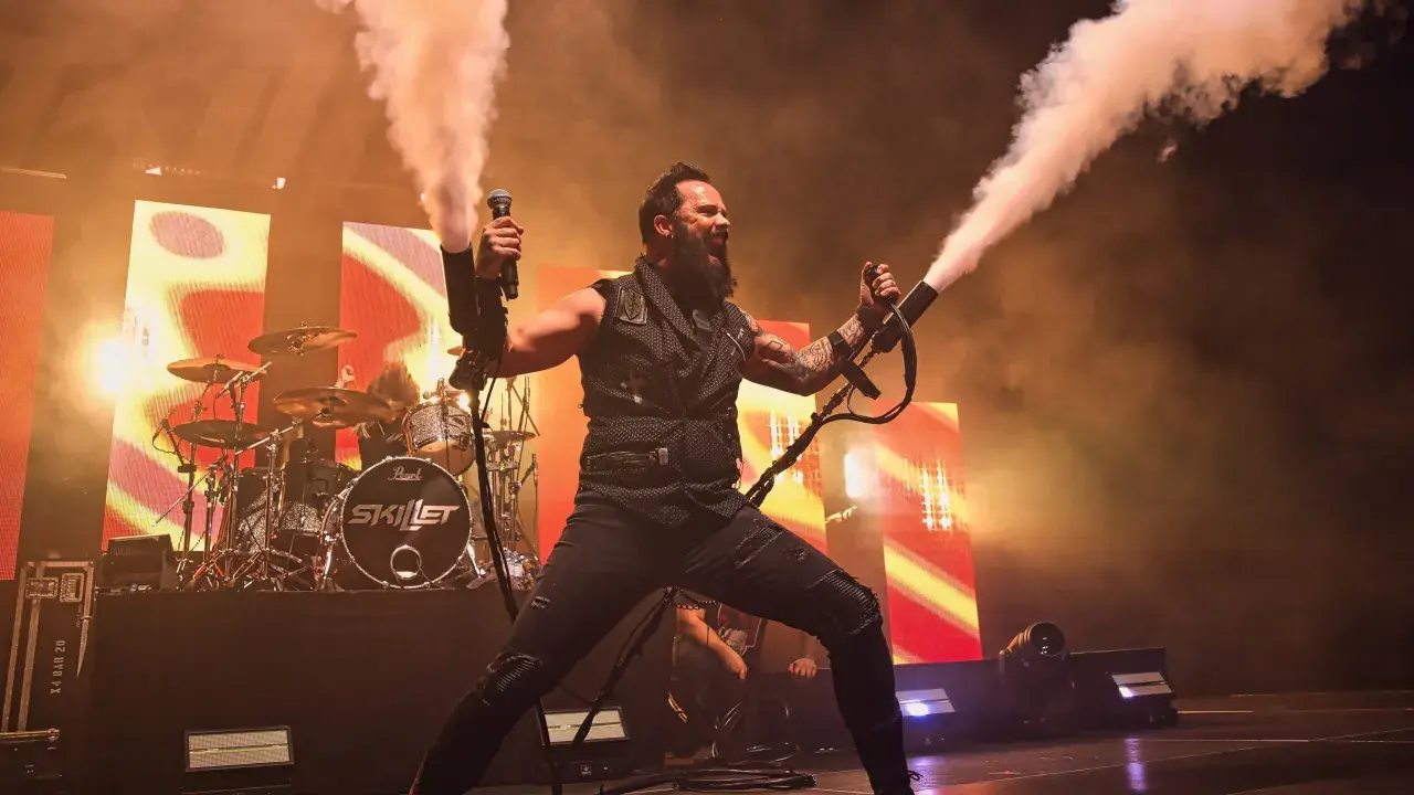 Skillet na koncercie w Warszawie, wokalista John Cooper strzela dymem z ręki.