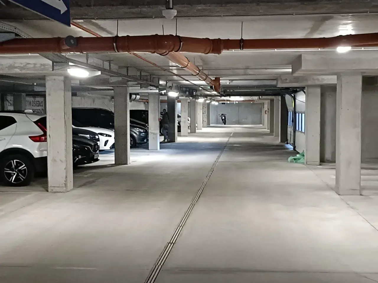 Wrocław Główny parking cennik: podziemny parking z samochodami, rurami i motocyklem w oddali.