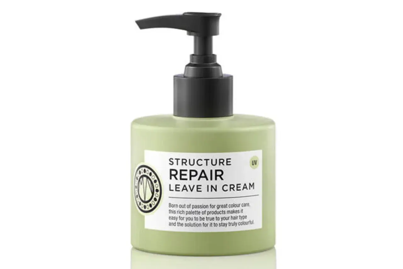 En ljusgrön flaska med pumpdispenser, märkning "Structure Repair Leave In Cream" för torrt hår.
