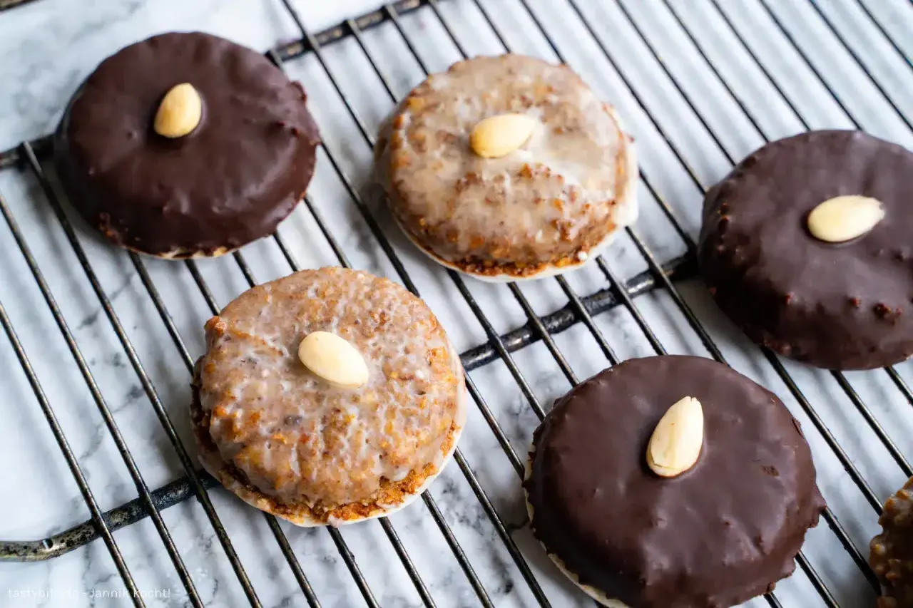 Leckeres Rezept für Elisenlebkuchen: Dunkel und hell glasierte Lebkuchen mit Mandeln auf einem Gitter.