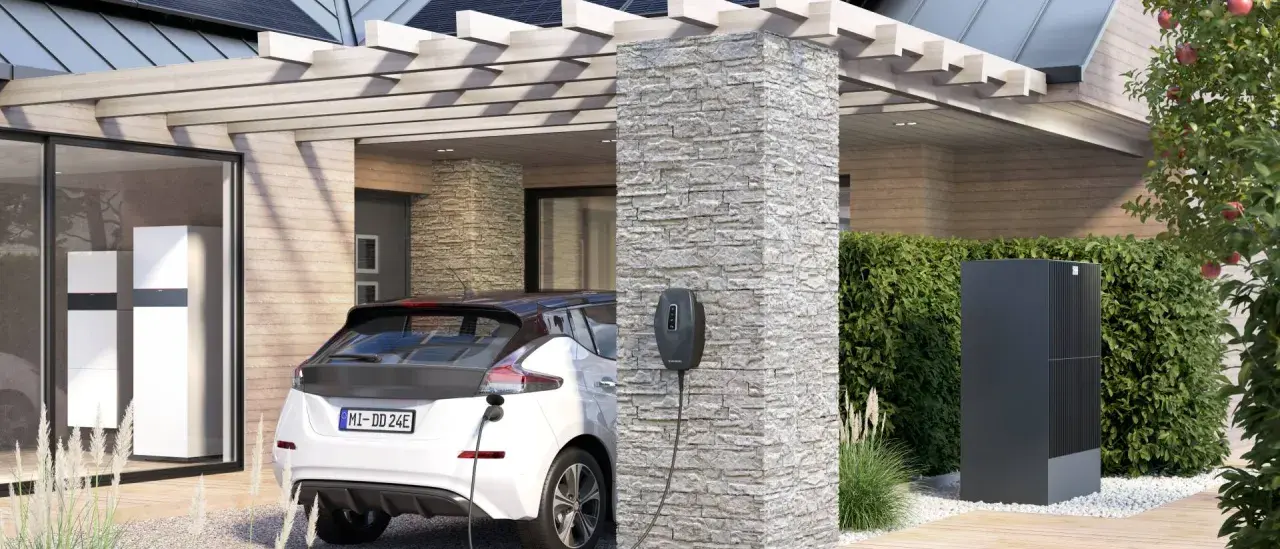 Ein weißes Elektroauto lädt an einer Ladesäule. Im Hintergrund ein modernes Haus mit Wärmepumpe und Solaranlage. Perfekt für die evu sperrzeit.