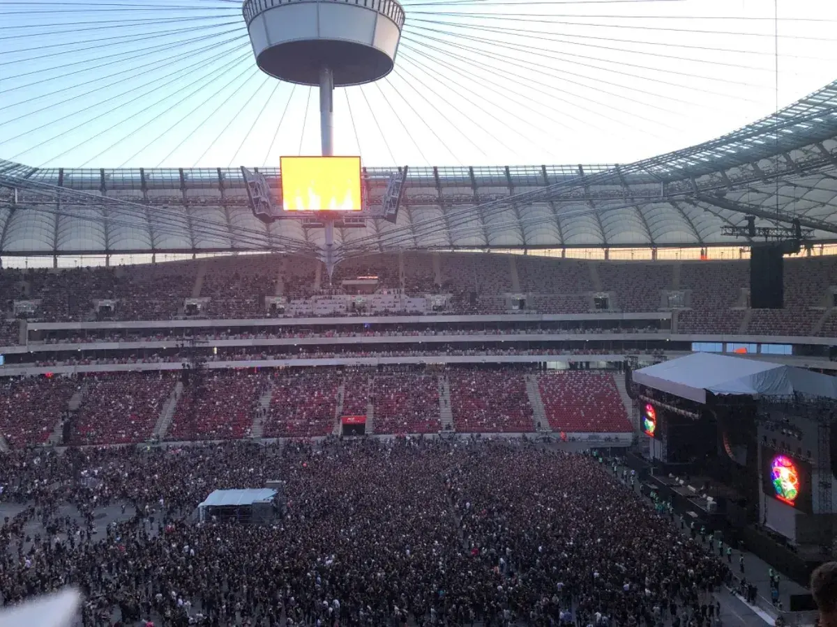 Tłum ludzi na koncercie na Stadionie Narodowym. Widok z góry na scenę i trybuny. Może to jedne z najgorszych miejsc na stadionie narodowym, bo daleko od sceny.