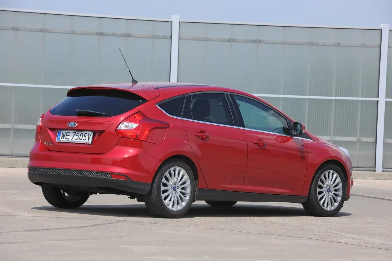 Czerwony Ford Focus MK3 kombi, gotowy do wymiany żarówki stopu.