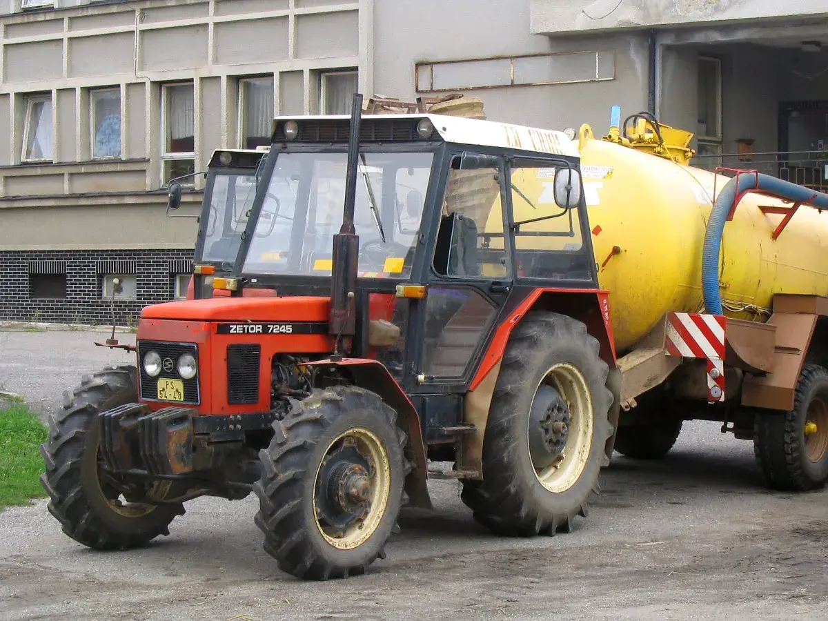 Czerwony Zetor 7245 z żółtym beczkowozem. Ile ma koni? Ten model zazwyczaj ma około 70 KM.